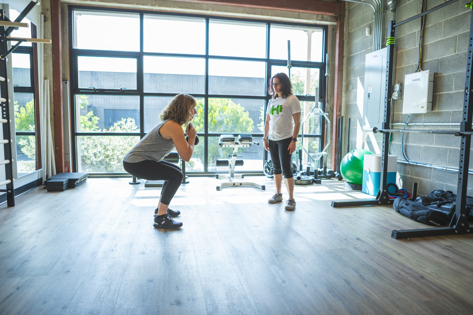 Female personal trainer at Hyatt Strength + Wellness reviewing a gym workout plan with her female client.